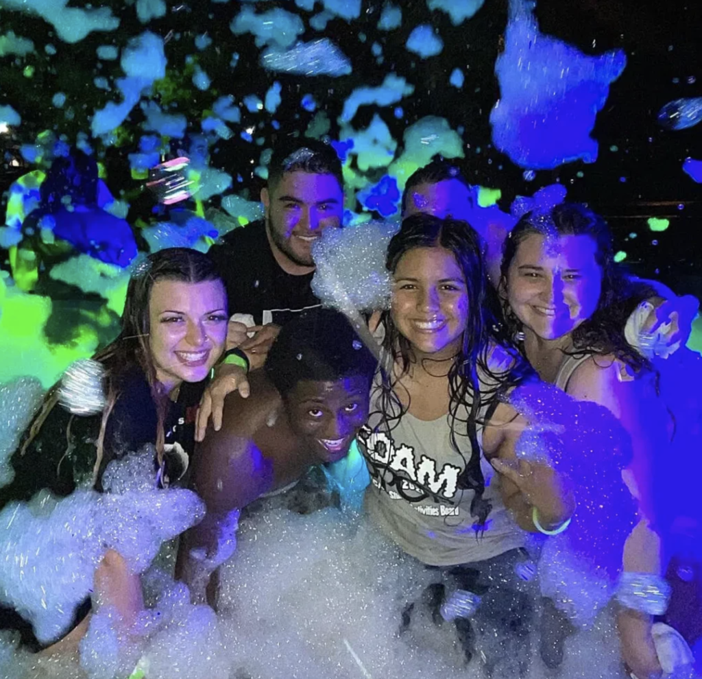 A group of teenagers smiling and covered in bubbles