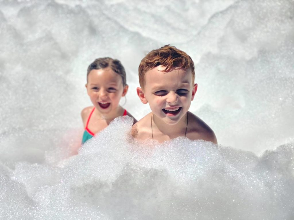 Two small children laughing in a pile of foam