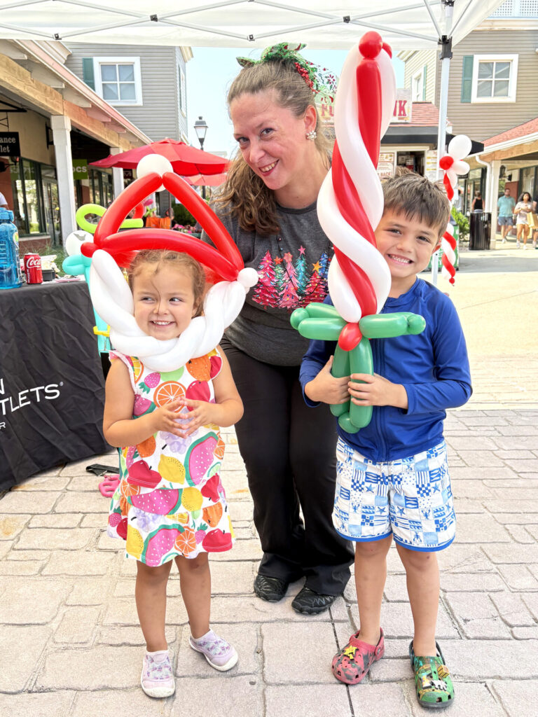 An outdoor shopping center hosting Christmas in July themed balloon twisting